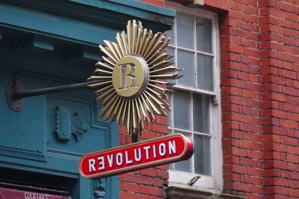 a red revolution sign hangs from a brick building