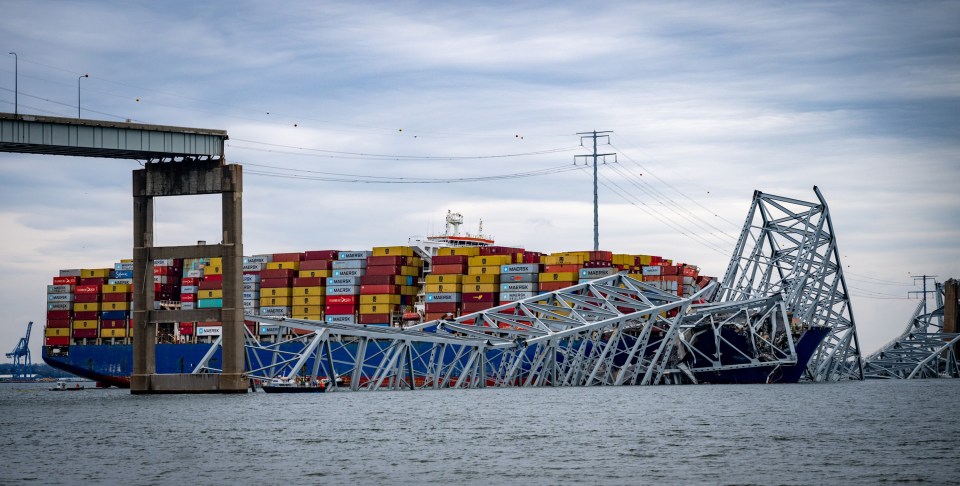 The cargo ship is seen caught under the jagged remains of the bridge