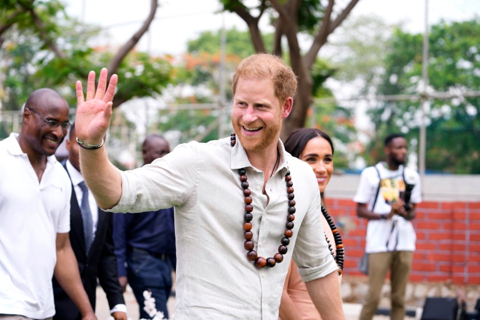 a man wearing a necklace of beads is smiling and waving