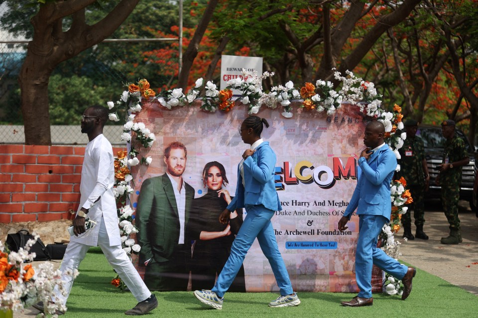 people walking in front of a welcome sign for prince harry and meghan