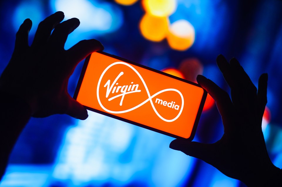 a person is holding a phone with the virgin media logo on it