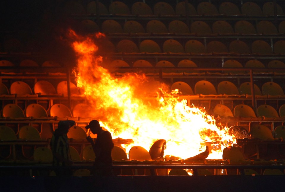 a man stands in front of a large fire in a stadium