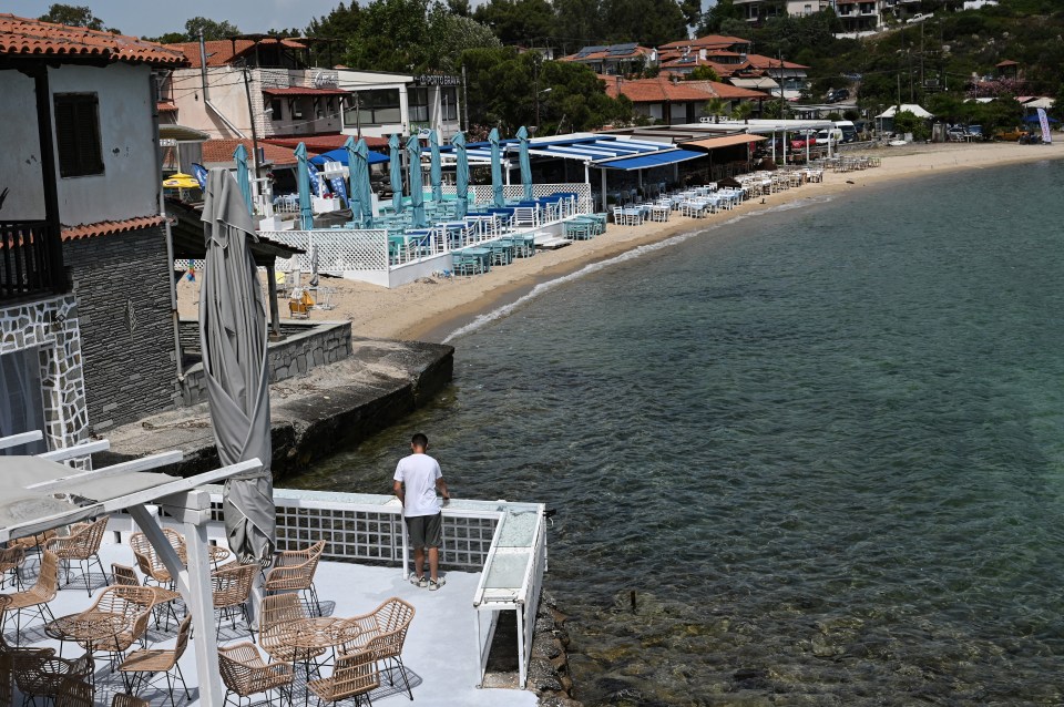 a man stands on a balcony overlooking the ocean