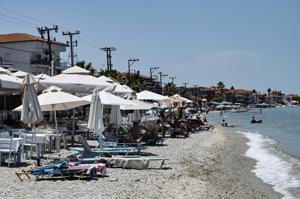 a row of tables and chairs on a beach with umbrellas