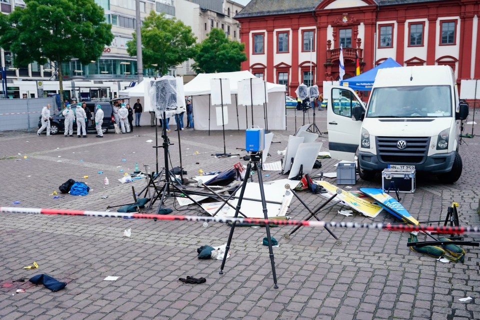 Forensics officers stand behind a smashed stall on the market square