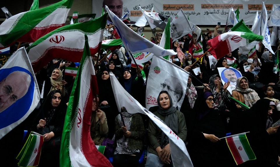a crowd of people holding flags with a picture of a man on them