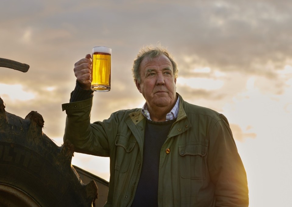 a man in a green jacket is holding a glass of beer