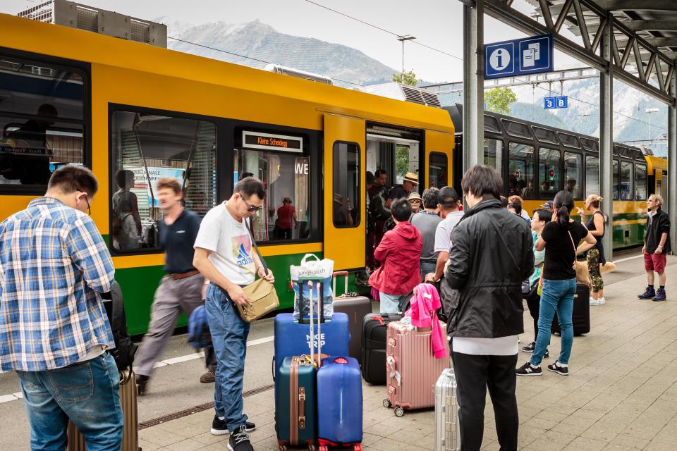 KABA2E Wengen, Bernese Oberland, Switzerland - JULY 31, 2017 : Tourists with luggage and the train from Lauterbrunnen to Kleine Scheidegg in the railwaystati