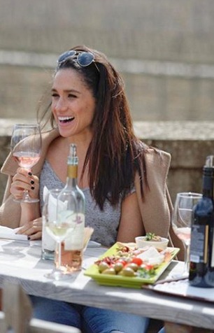 a woman is sitting at a table holding a glass of wine .