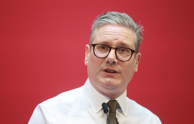 a man wearing glasses and a white shirt stands in front of a red background