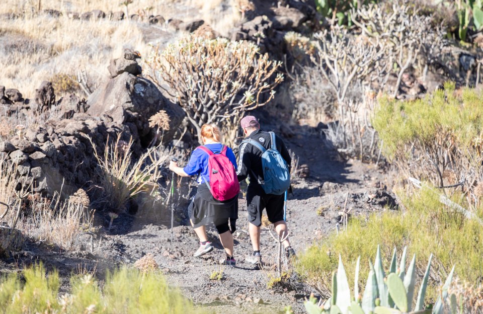 a man and a woman are hiking down a dirt path