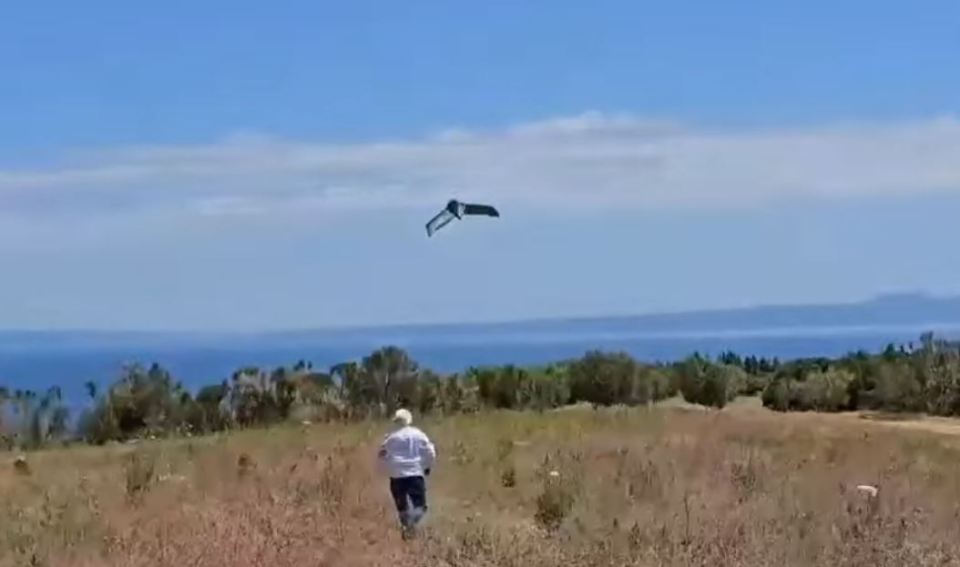a man is walking in a field with a kite flying in the sky .