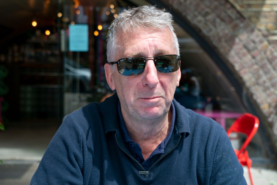 a man wearing sunglasses and a blue shirt looks at the camera