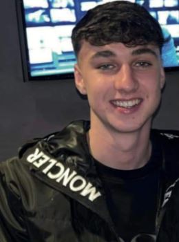 a young man wearing a black moncler jacket is smiling for the camera .