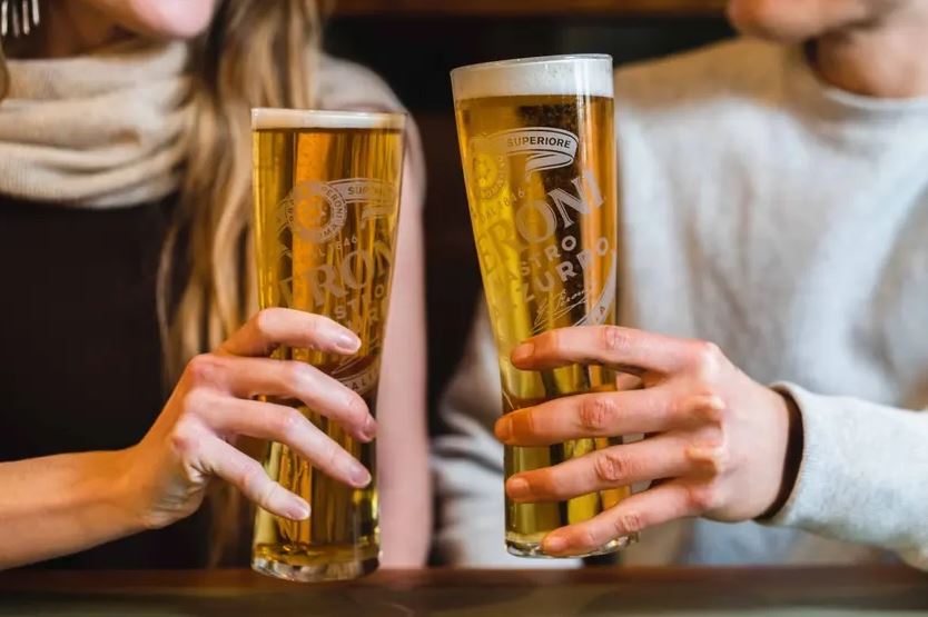 a man and a woman are toasting with two glasses of beer .