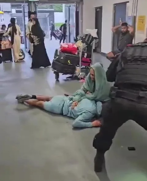 a man is laying on the floor in an airport terminal .