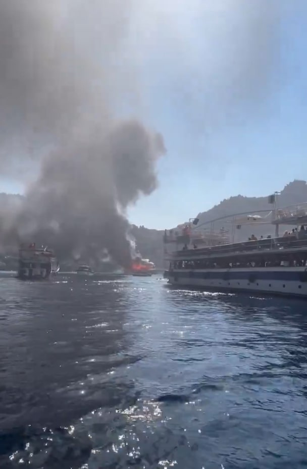 Onlookers watch in panic as the fire engulfs the boat