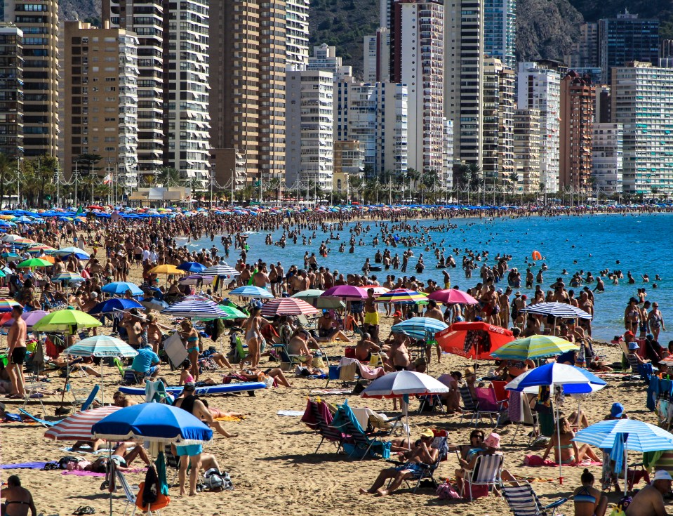 Benidorm, Alicante, Spain- October 9, 2021: People sunbathing on Levante beach on a Sunny day of Autumn in Benidorm