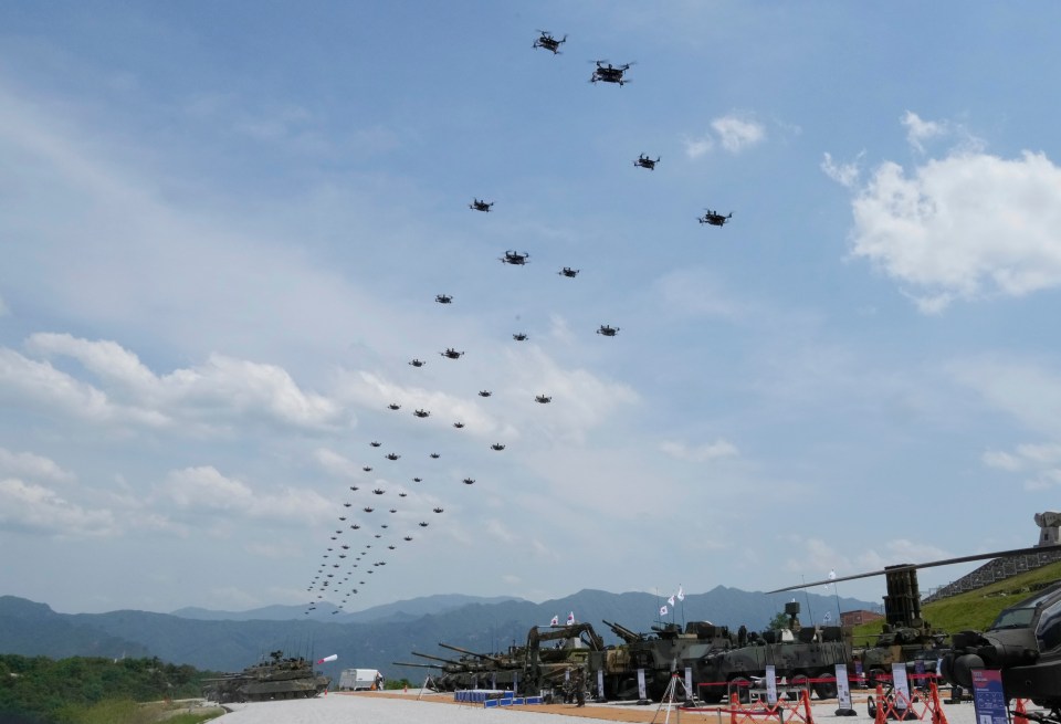 a bunch of helicopters are flying over a military base