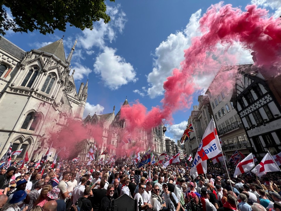 a crowd of people holding flags and smoke coming out of a building that says eve
