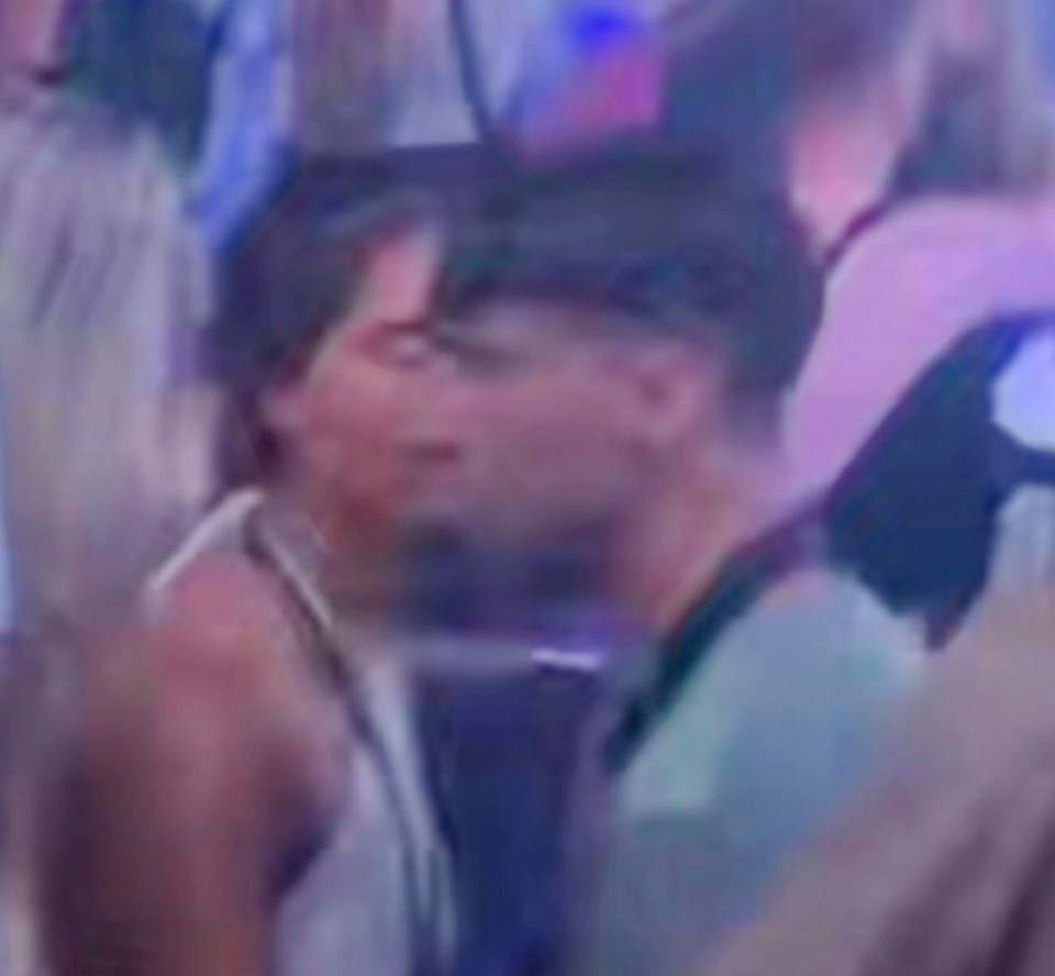 a man and woman are kissing in a crowd of people at a party .