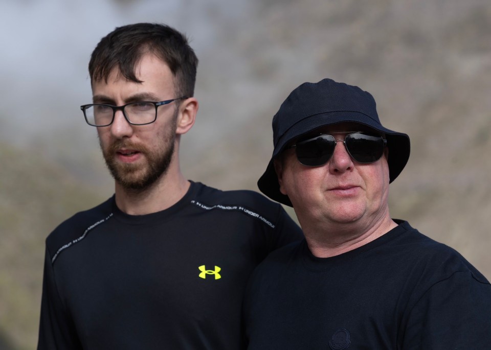 a man wearing a black under armour shirt stands next to another man