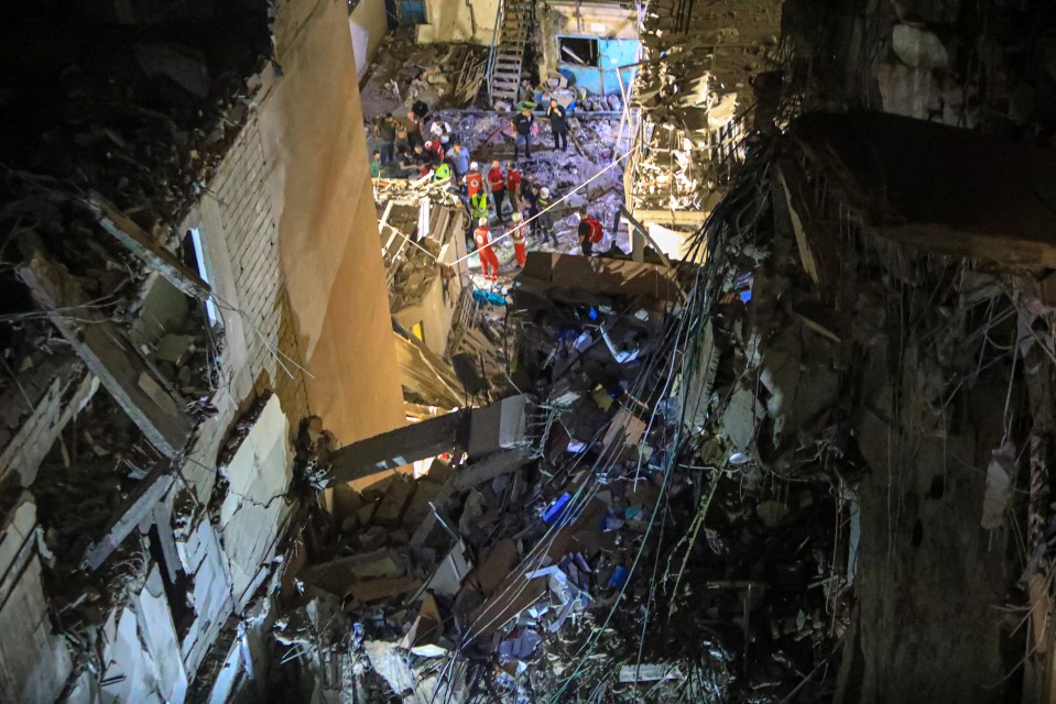 a group of people are standing in the rubble of a building