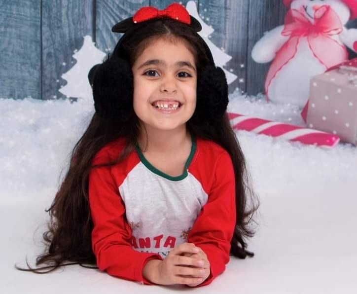 a little girl wearing ear muffs and a santa shirt
