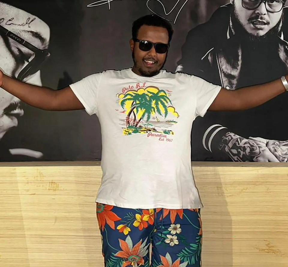 a man wearing a white shirt that says paradise on the beach