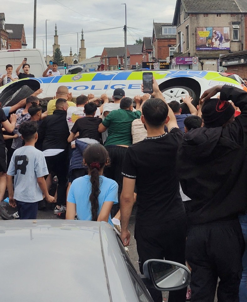 a crowd of people are gathered around a police vehicle