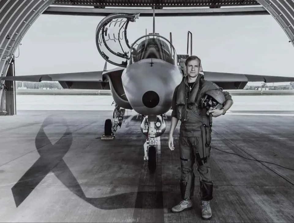 a man wearing a helmet stands in front of a fighter jet