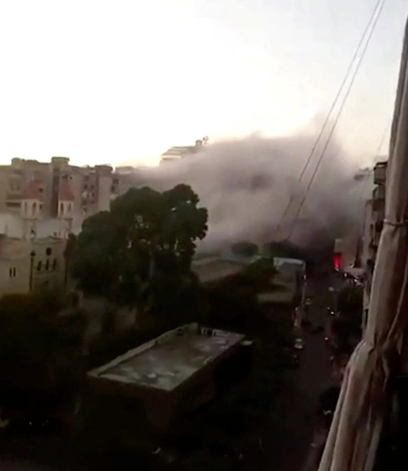 a bird is flying over a city with smoke coming out of a building