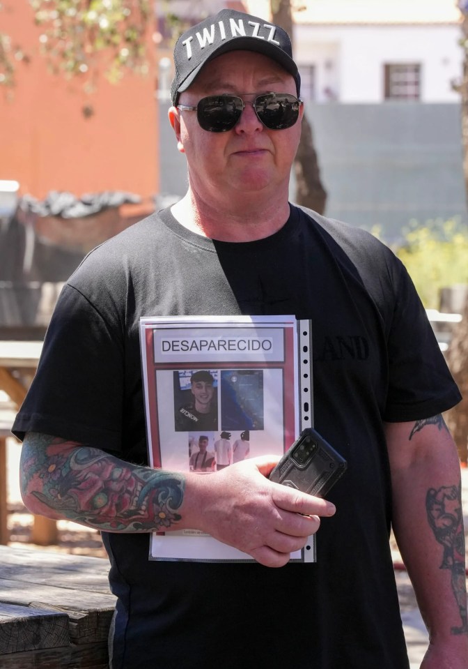 a man wearing a twin71 hat holds a flyer for a missing person