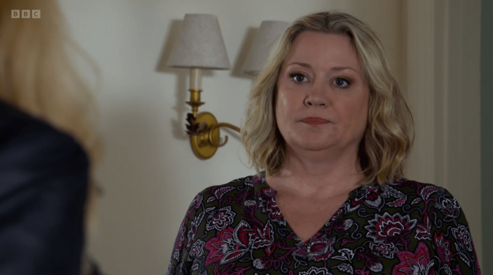 Screenshot of a woman with blonde hair wearing a floral blouse.