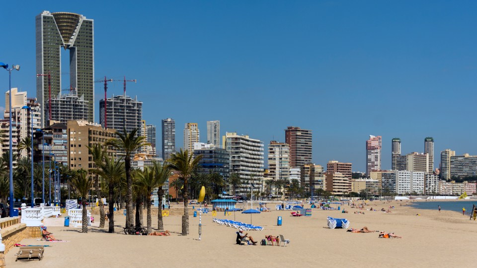 tourists enjoying the sunshine while sunbathing on a glorious Spring day on Poniente beach, Spain.