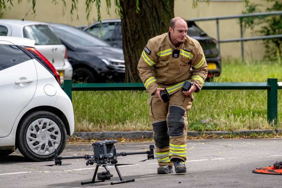 a man in a fireman 's uniform stands next to a drone