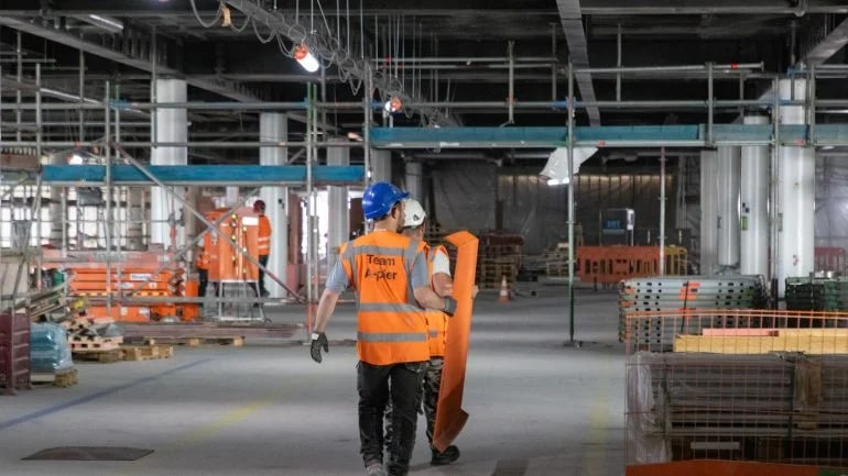 two construction workers wearing orange vests that say team a-plex