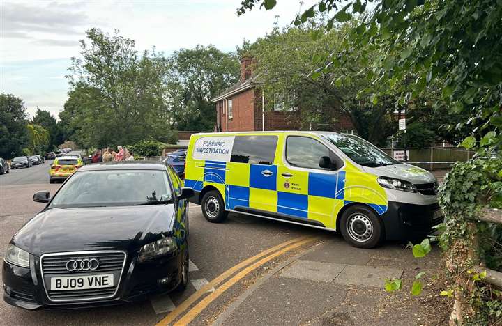 a forensic investigation van is parked on the side of the road next to a black car .