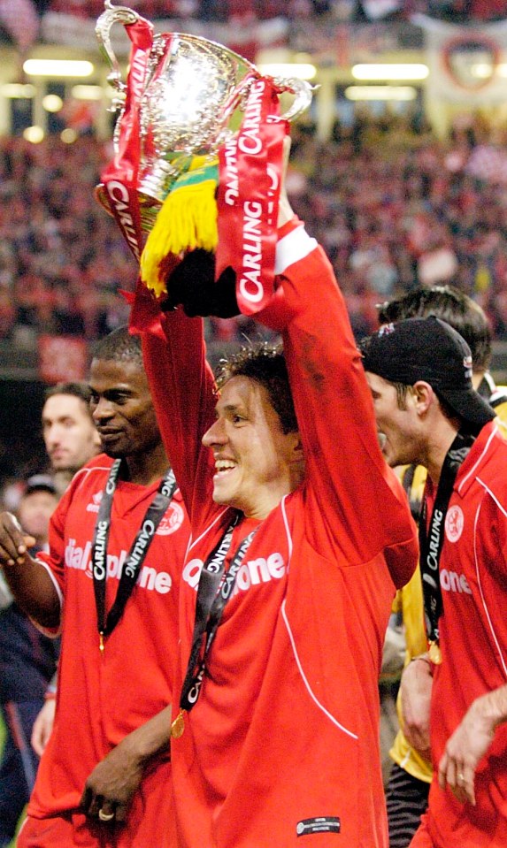 a man in a carling shirt holds up a trophy