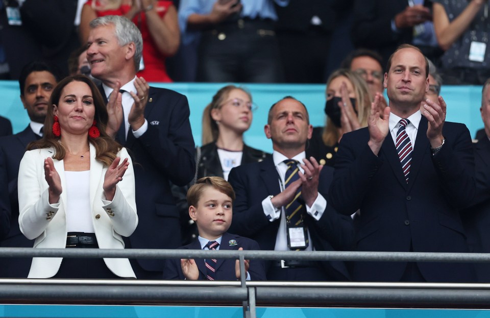 a man in a suit and tie applauds while a woman in a white shirt looks on