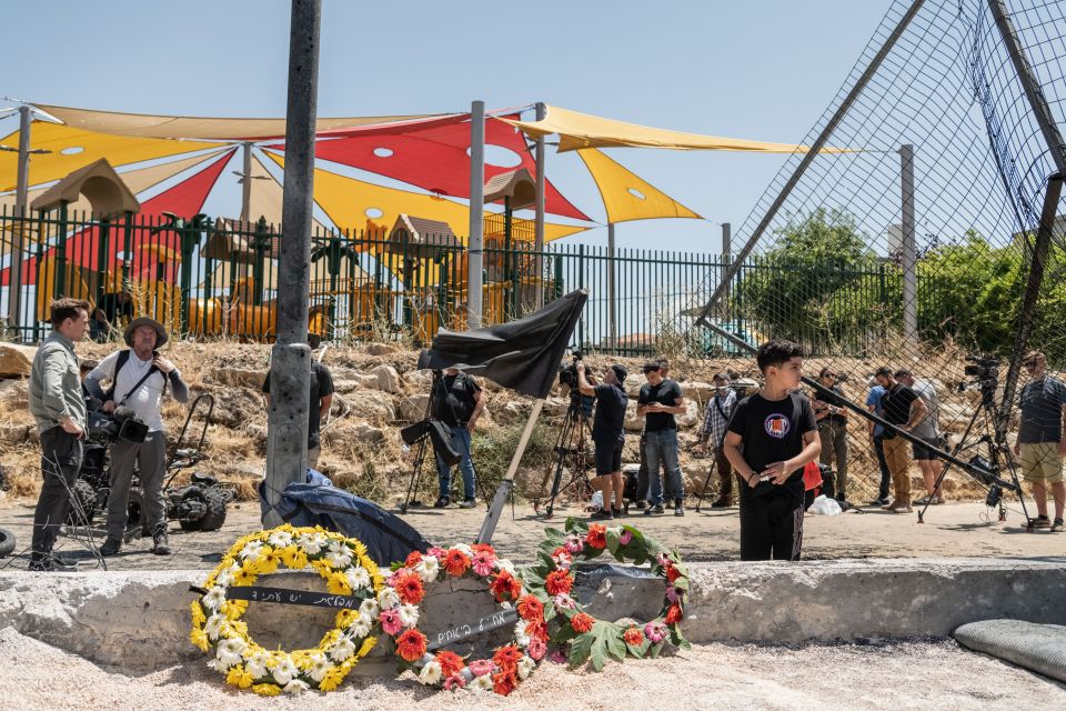 a group of people are gathered around a grave with flowers and a wreath that says " i am a soldier "
