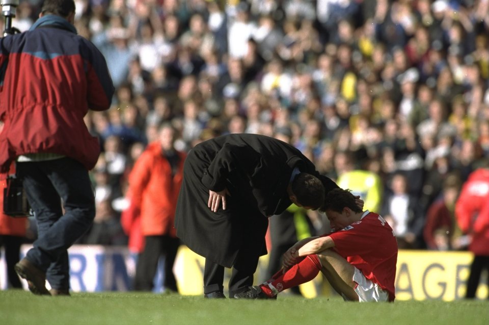 a man kneeling on a soccer field with a yellow sign behind him that says agri
