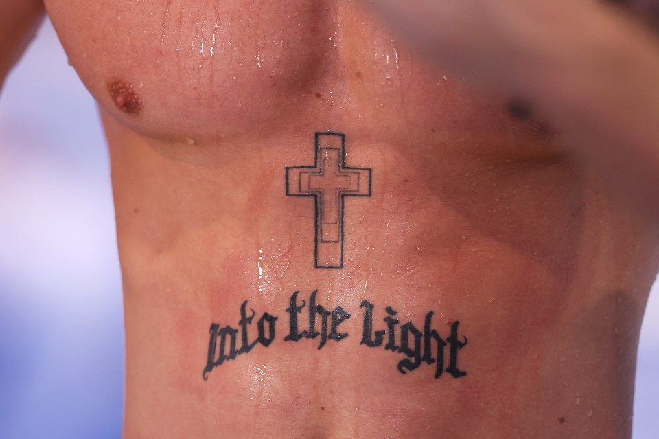 a man has a tattoo of a cross and the words into the light