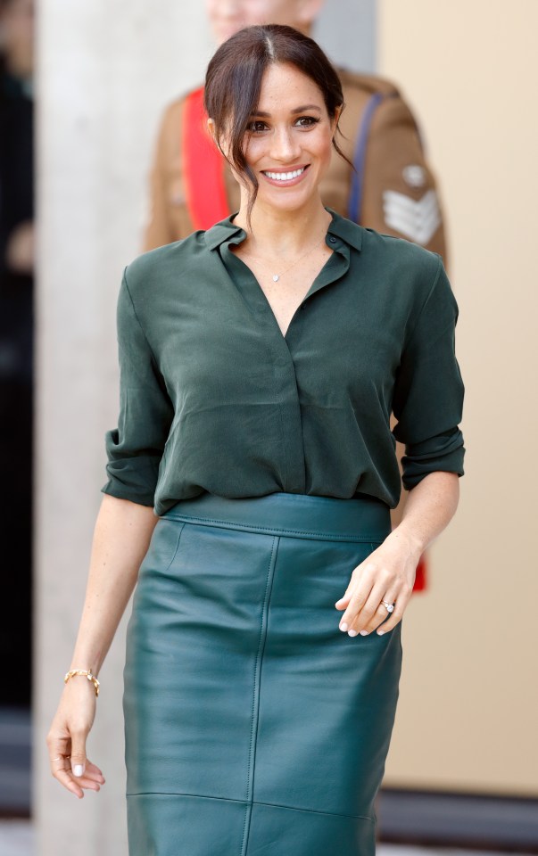 a woman wearing a green shirt and a green skirt smiles