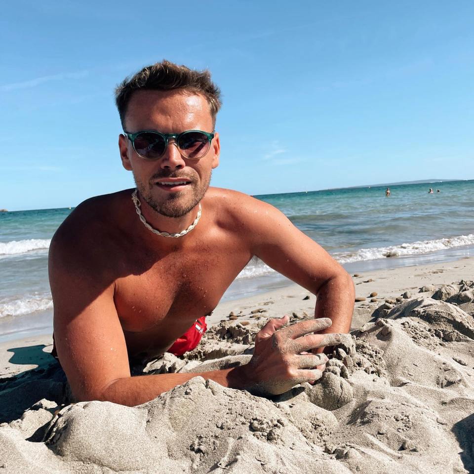 a shirtless man is laying in the sand on the beach