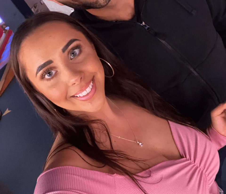 a woman in a pink top smiles next to a man in a black jacket