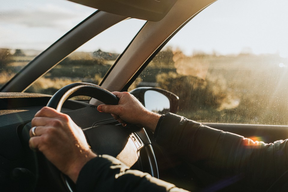 a person driving a car with their hands on the steering wheel