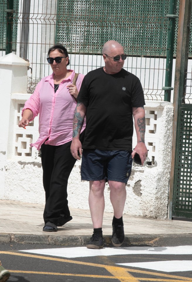 a woman in a pink shirt is walking with a man in a black shirt