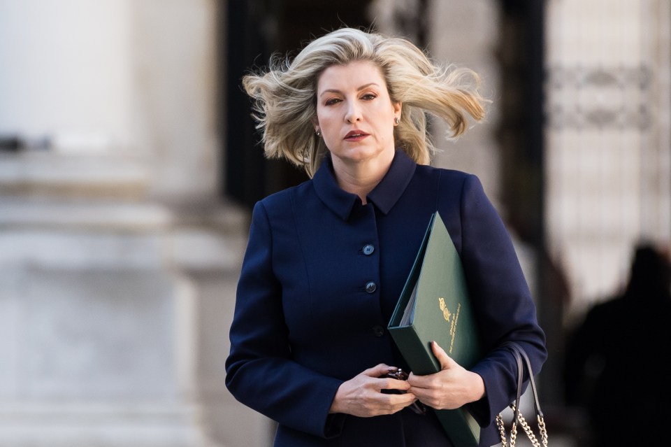 a woman in a blue coat carrying a green binder