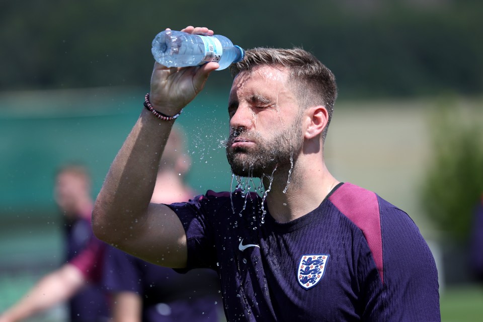 a man in an england shirt is pouring water on his face